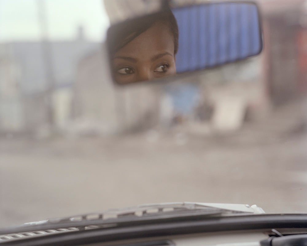 A woman's eyes reflected in a car's rear-view mirror
