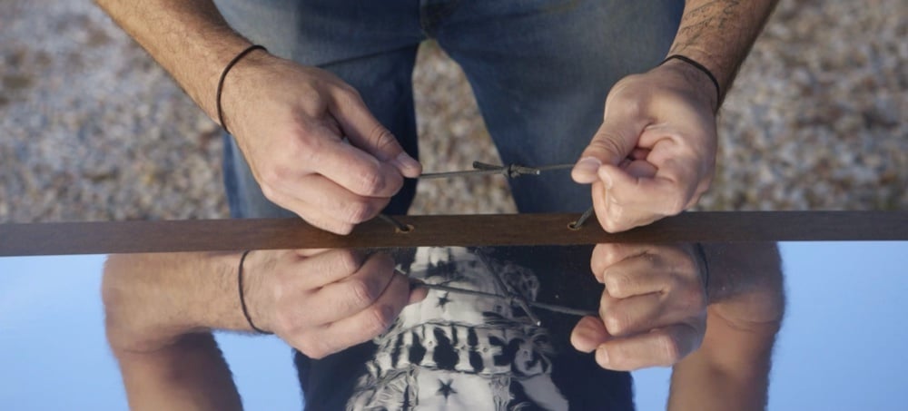 Hands gripping the edge of a mirrored shield, a still from the How To Build Mirror Shields video